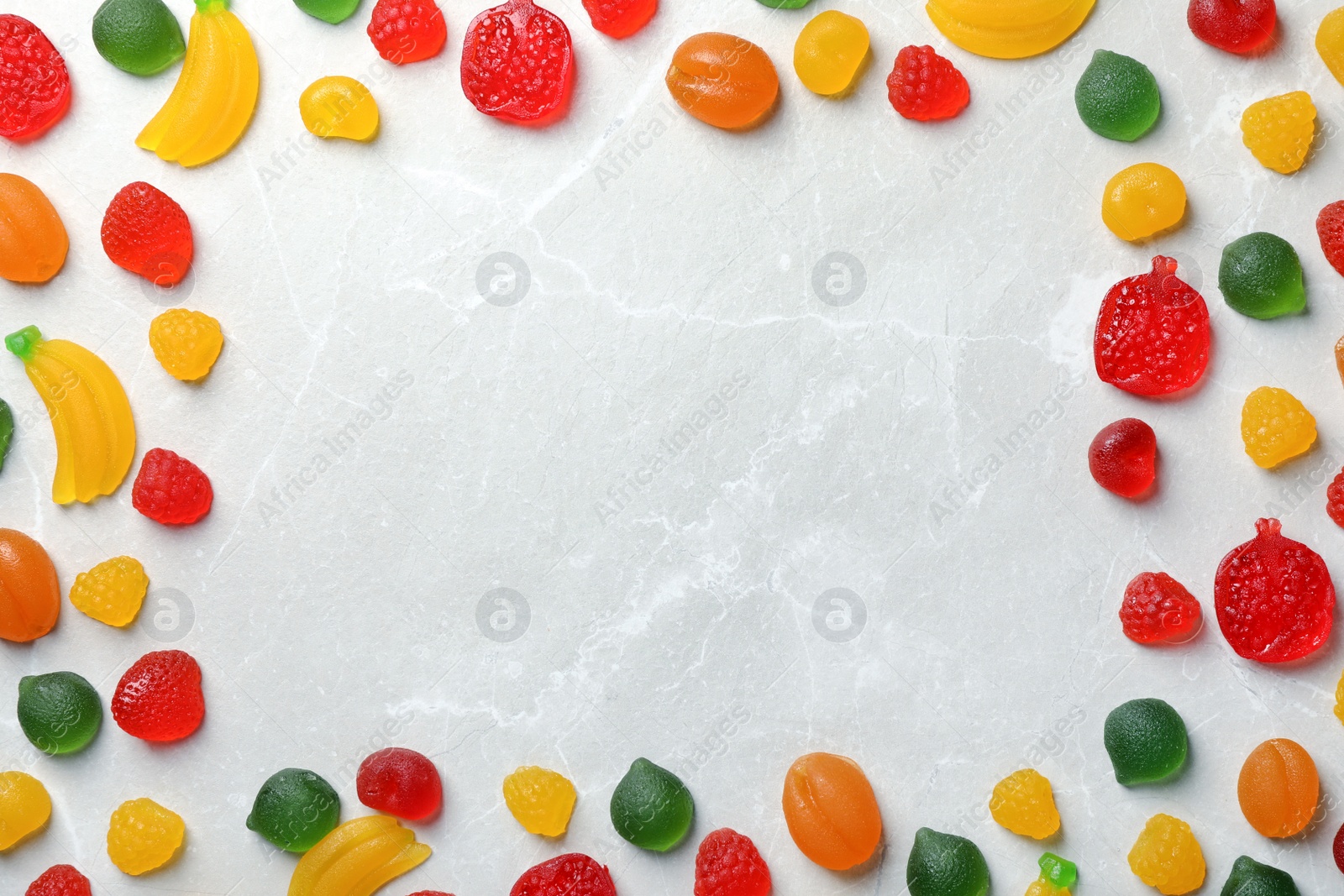 Photo of Frame of delicious gummy candies on light grey table, flat lay. Space for text