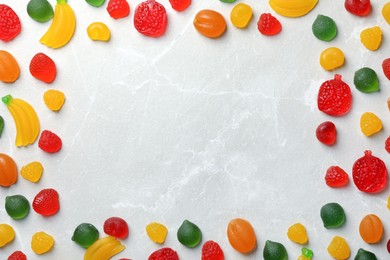 Photo of Frame of delicious gummy candies on light grey table, flat lay. Space for text