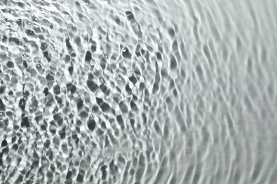 Rippled surface of clear water on light grey background, top view