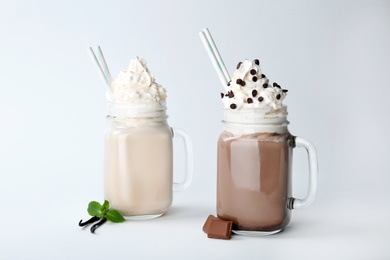 Photo of Mason jars with delicious milk shakes on white background