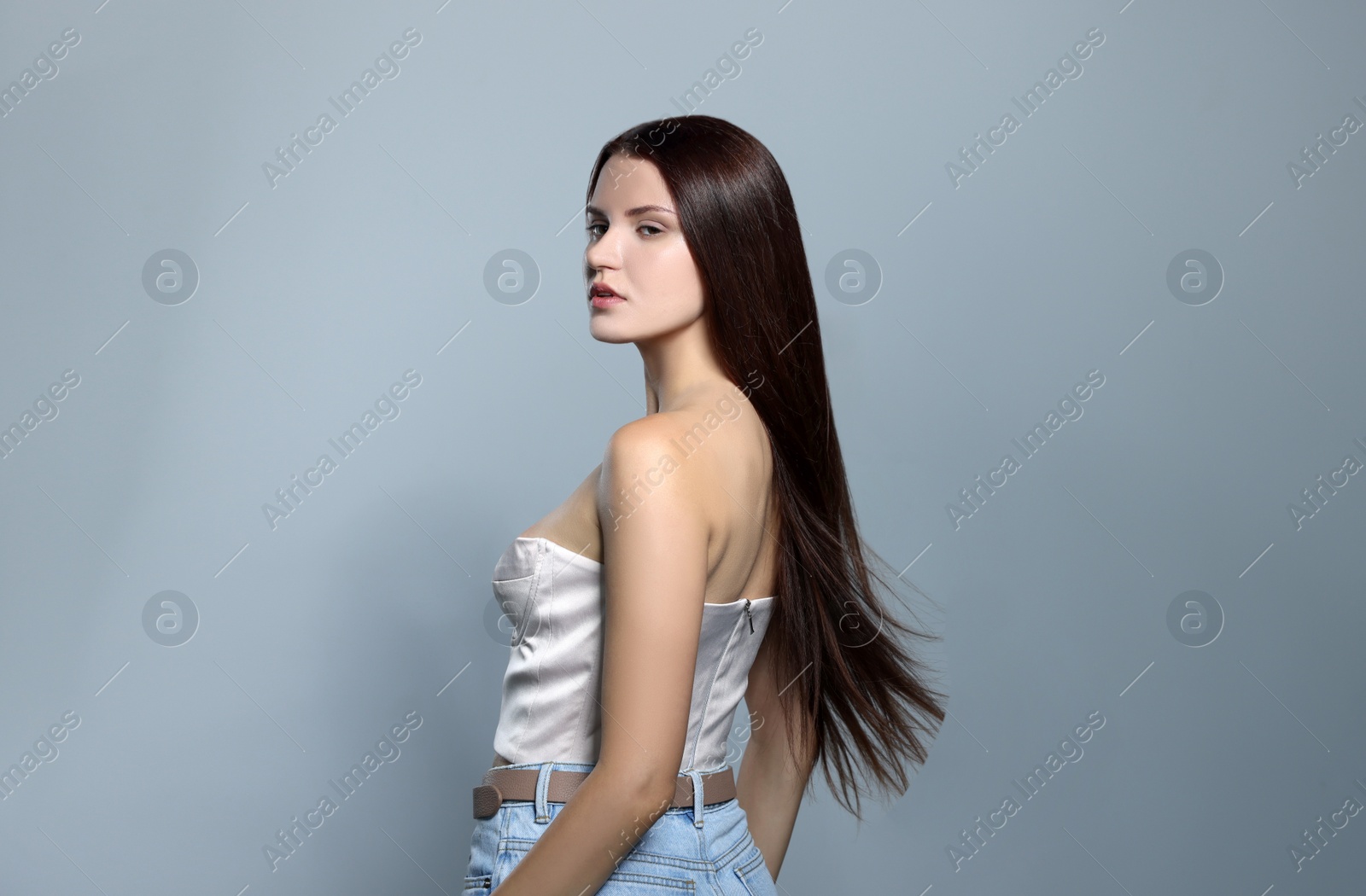 Photo of Portrait of beautiful young woman with healthy strong hair on light gray background