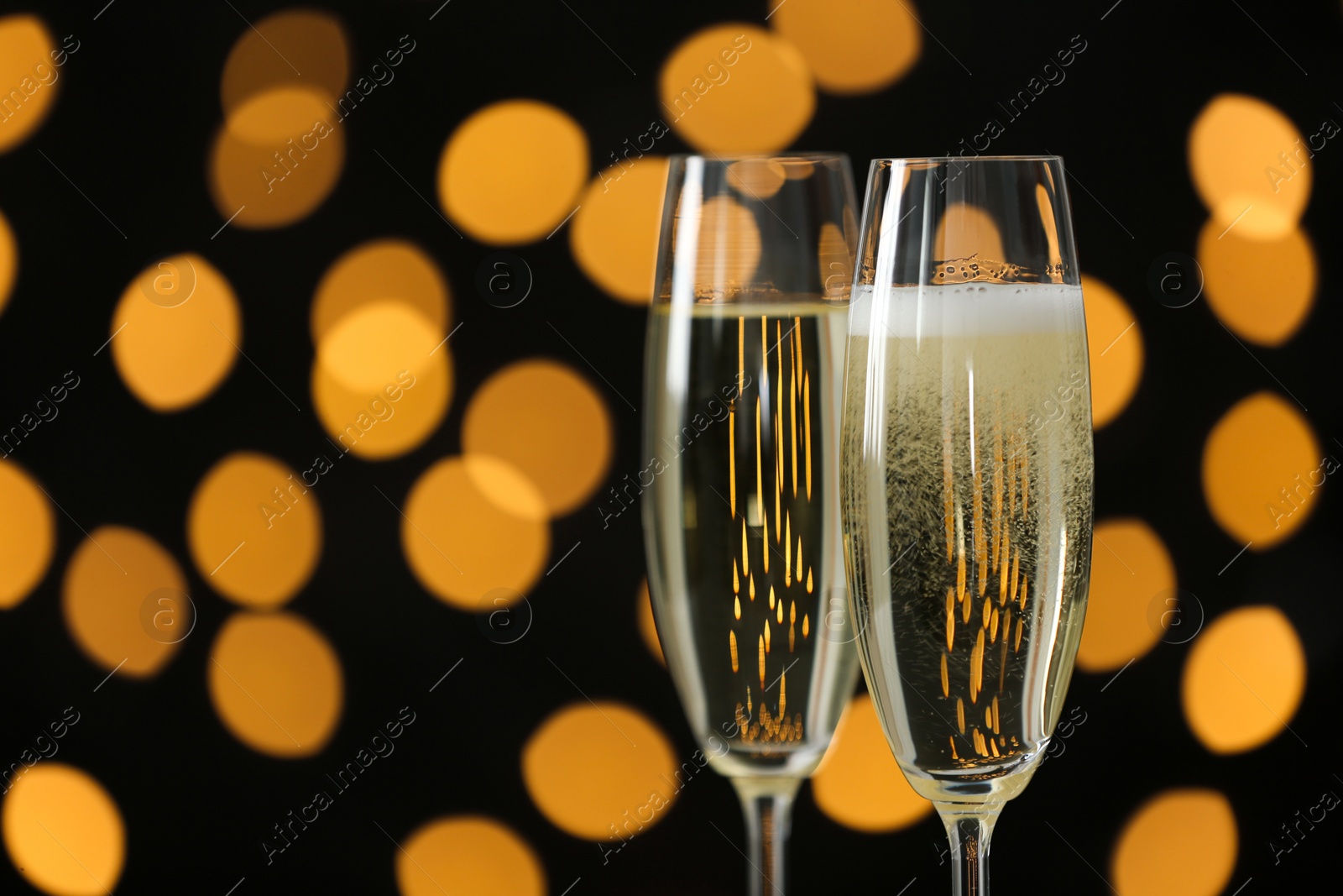 Photo of Glasses of champagne against blurred lights. Space for text