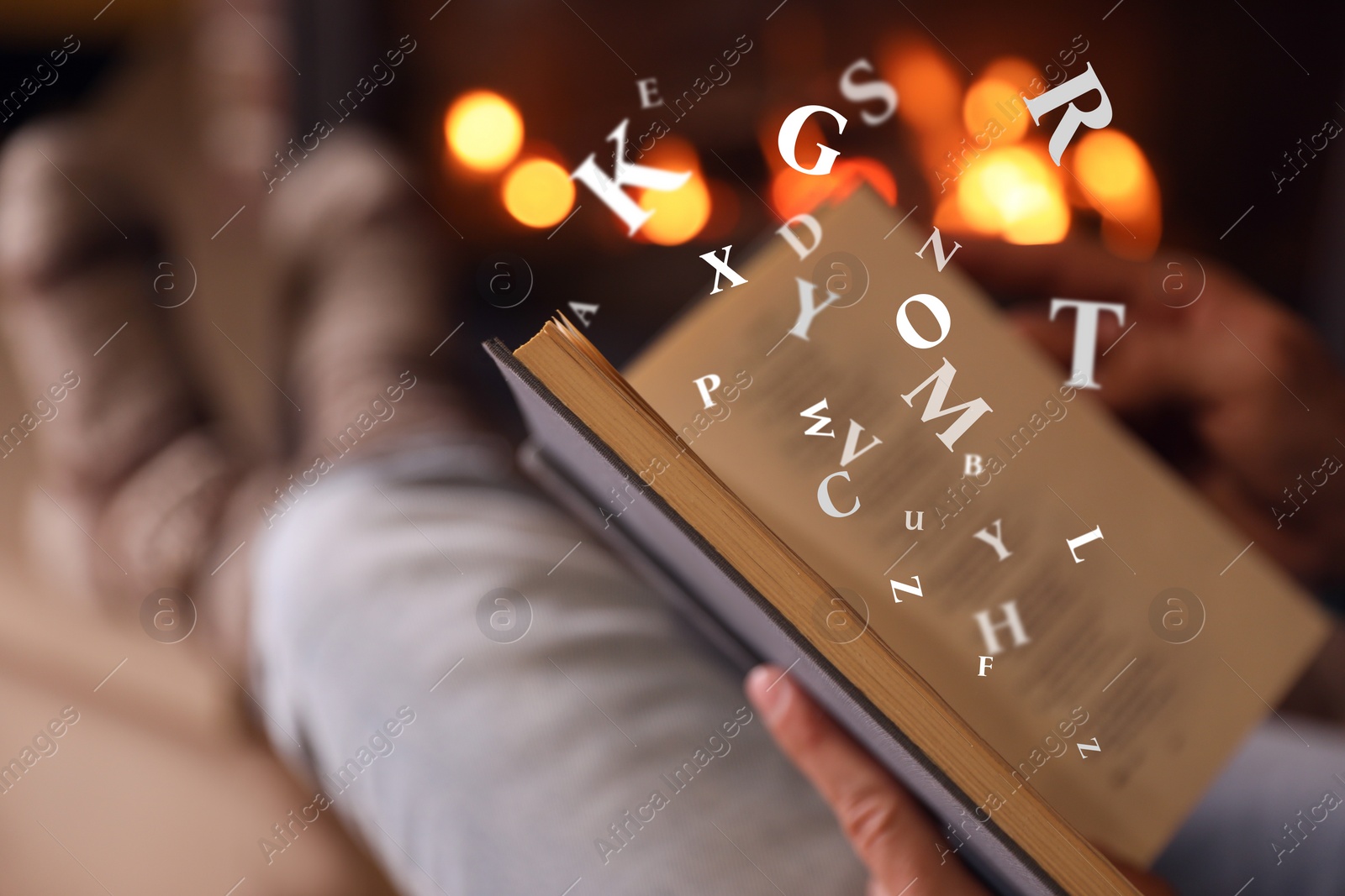 Image of Man reading book with letters flying over it near fireplace at home, closeup