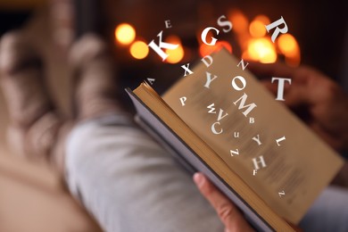 Image of Man reading book with letters flying over it near fireplace at home, closeup