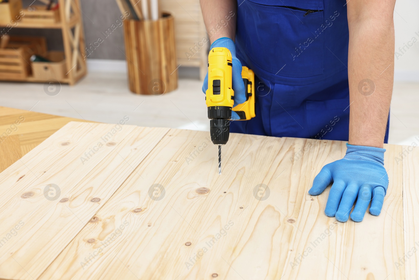 Photo of Young worker using electric drill at table in workshop, closeup