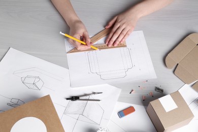 Photo of Woman creating packaging design at light wooden table, top view