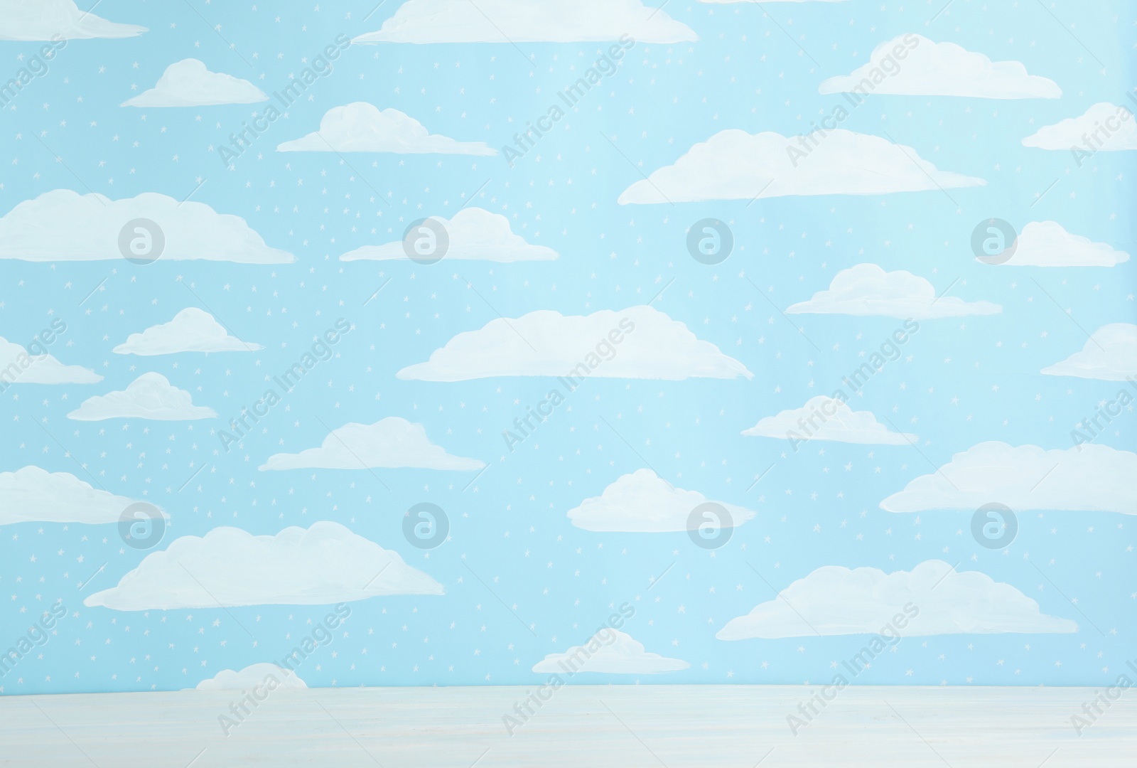 Photo of White wooden table near wall with painted blue sky. Idea for baby room interior