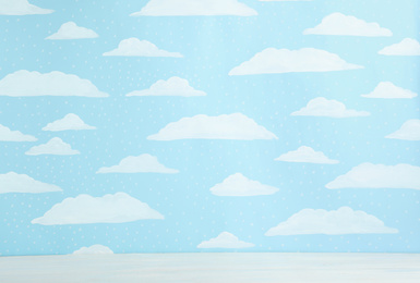 Photo of White wooden table near wall with painted blue sky. Idea for baby room interior