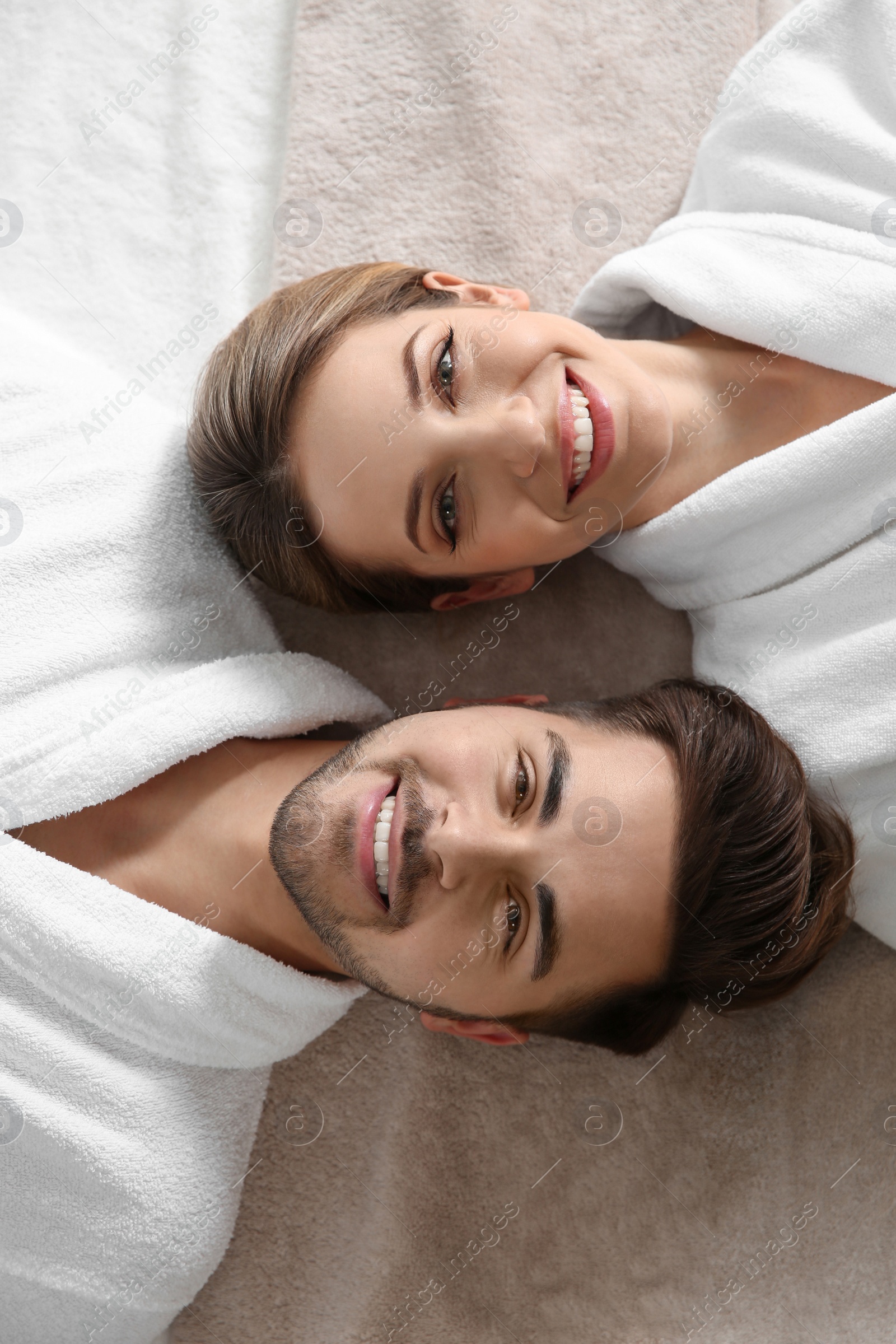 Photo of Happy young couple wearing bathrobes, top view. Visit to spa salon