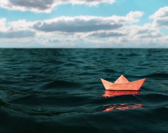 Image of White paper boat floating on sea. Space for text 