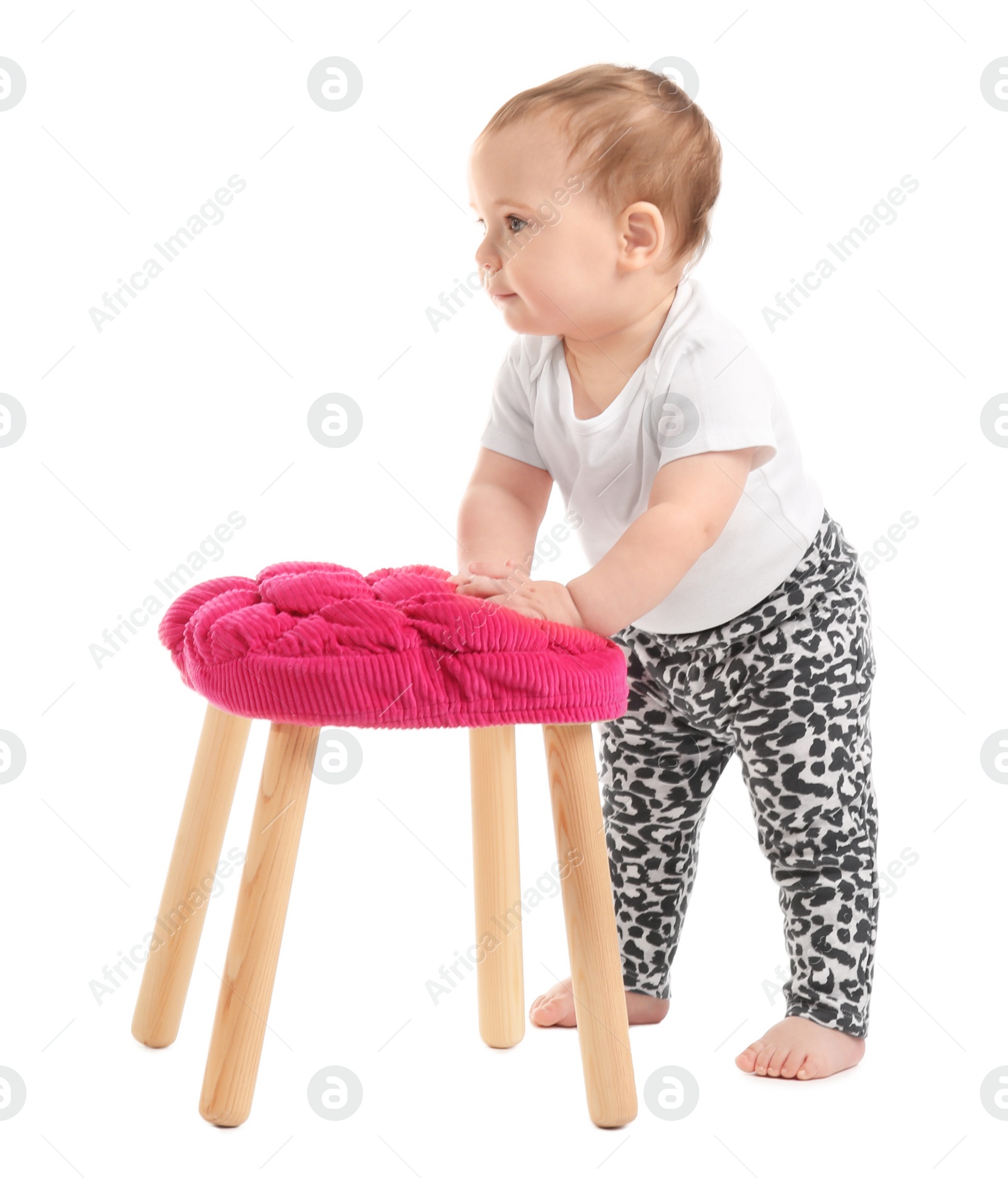 Photo of Cute baby holding on to stool on white background. Learning to walk