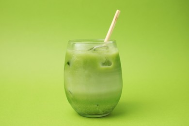 Photo of Glass of tasty iced matcha latte on light green background
