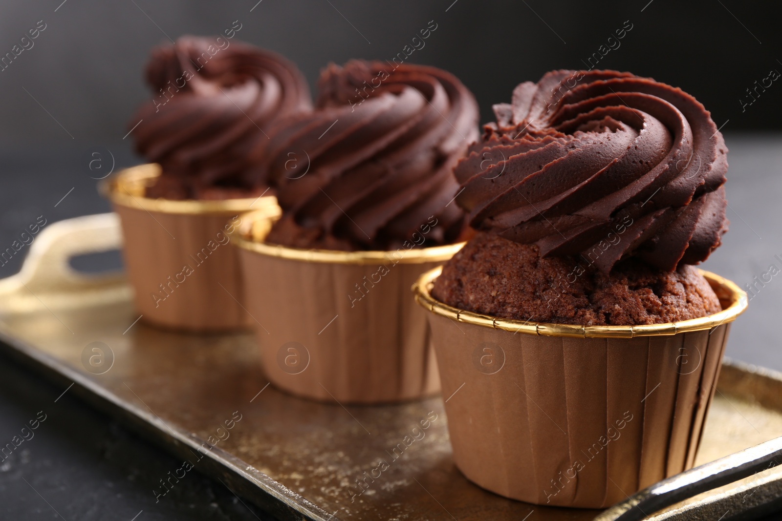 Photo of Delicious chocolate cupcakes on black textured table, closeup