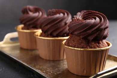 Photo of Delicious chocolate cupcakes on black textured table, closeup