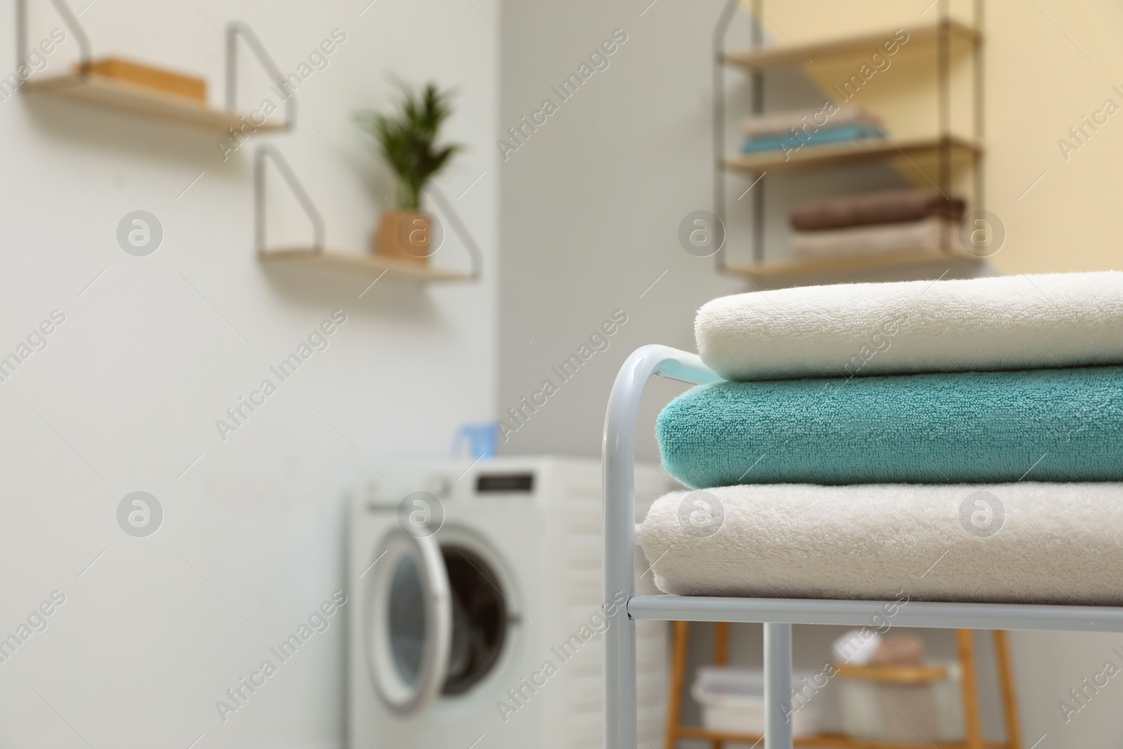 Photo of Stack of clean towels on table in laundry room. Space for text