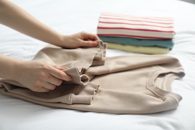 Woman folding clothes on bed, closeup view