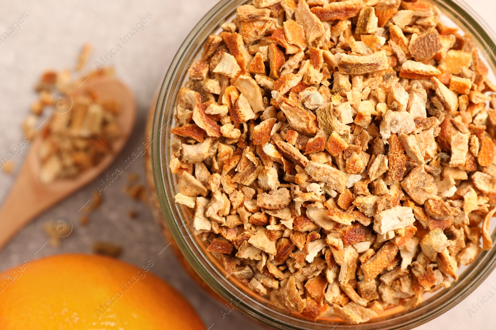 Photo of Jar of dried orange zest seasoning and fresh fruits on light grey table, closeup