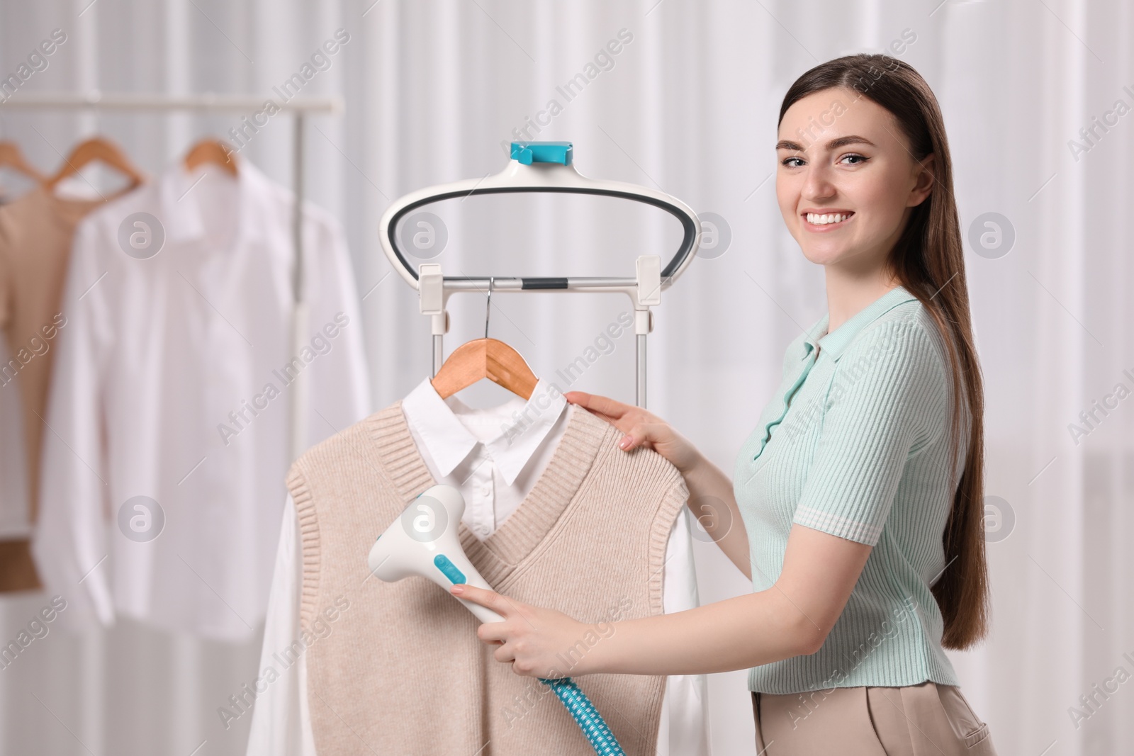 Photo of Woman steaming clothes on hanger at home