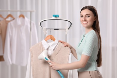 Photo of Woman steaming clothes on hanger at home