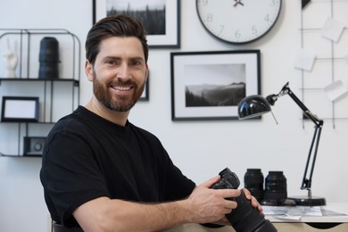 Photo of Professional photographer with digital camera at table indoors