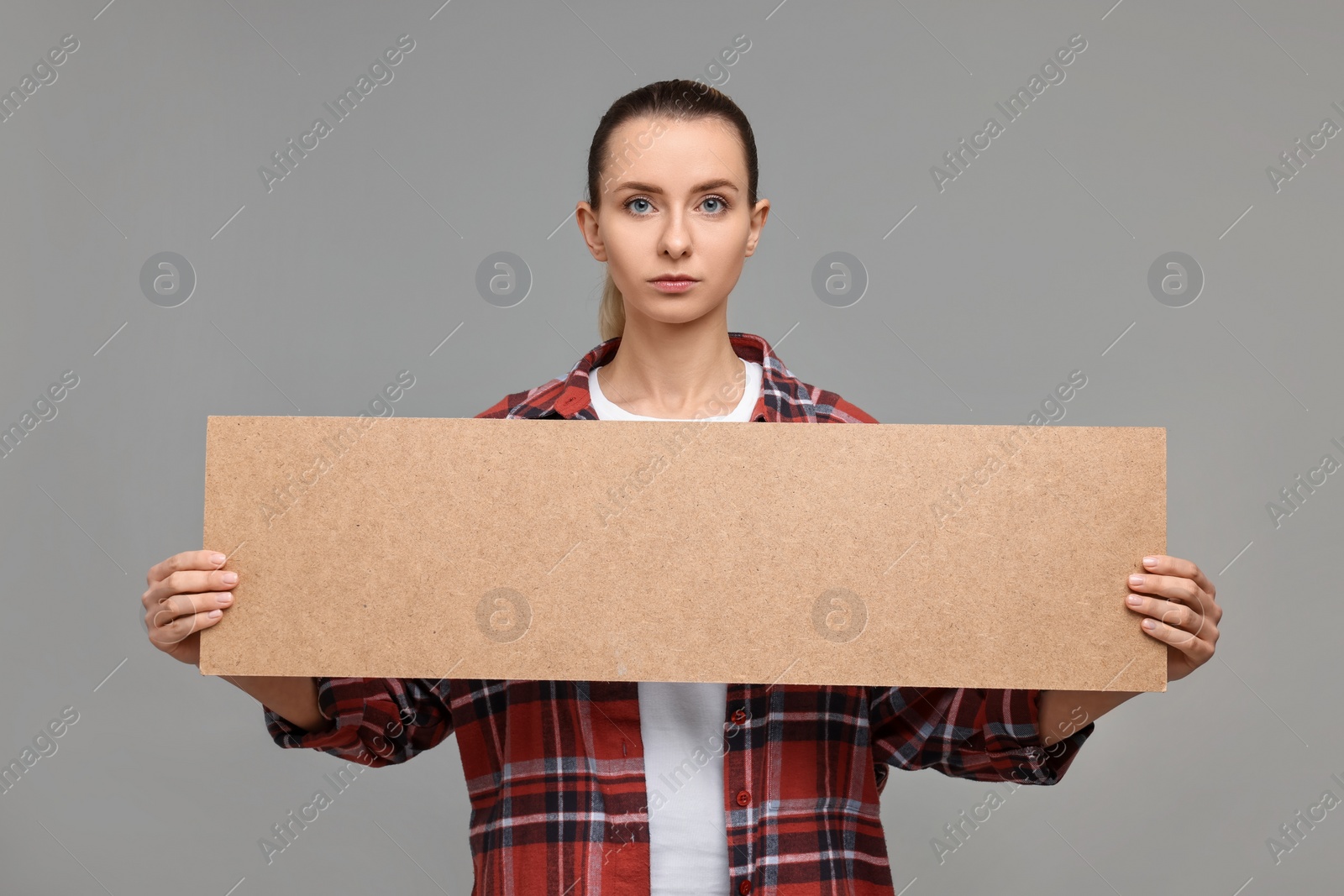 Photo of Woman holding blank cardboard banner on grey background, space for text