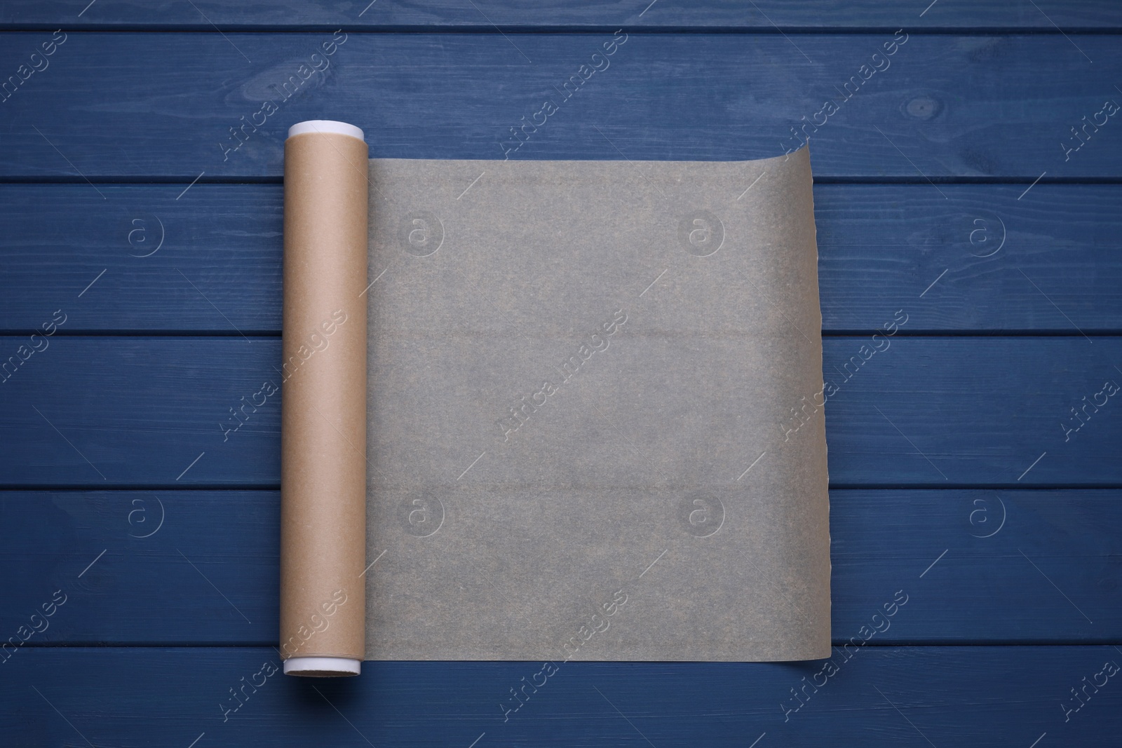 Photo of Roll of baking paper on blue wooden table, top view