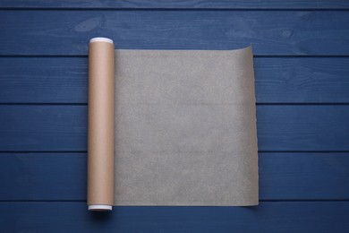 Photo of Roll of baking paper on blue wooden table, top view
