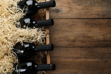 Crates with bottles of wine on wooden background, flat lay. Space for text