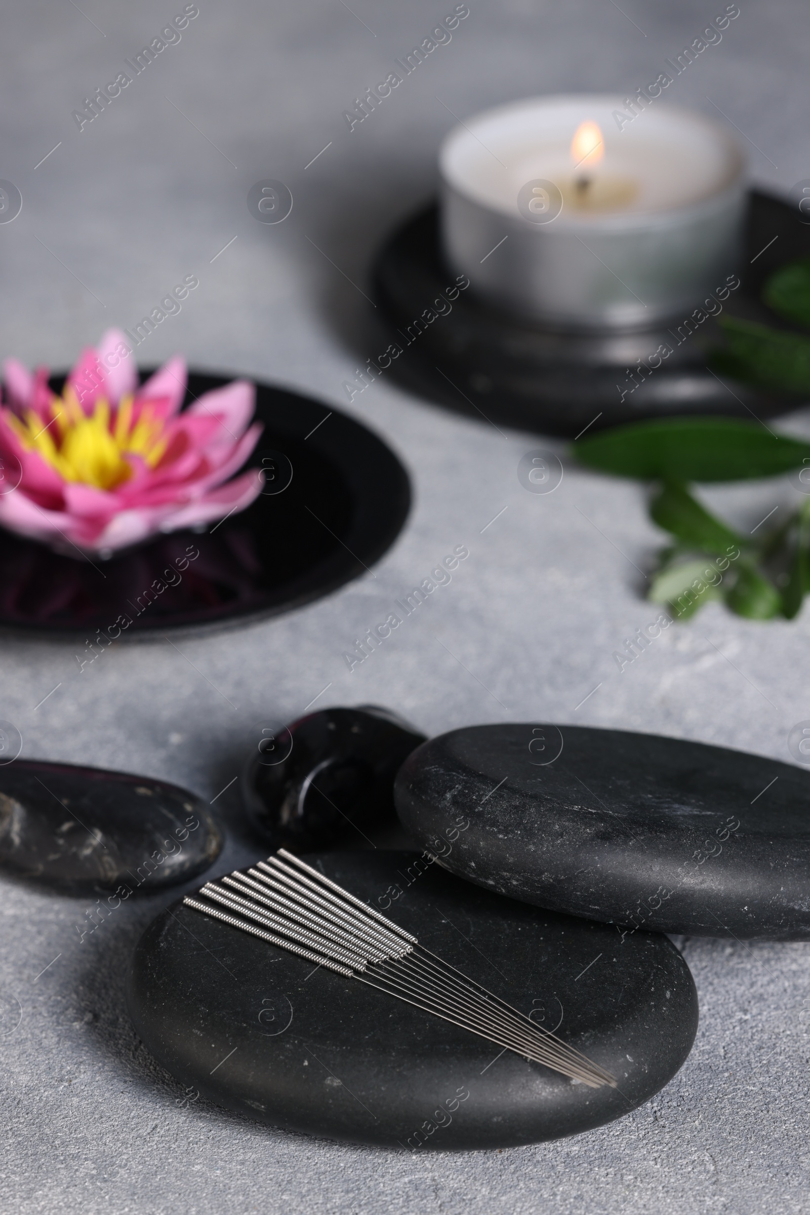 Photo of Stones with acupuncture needles on grey table