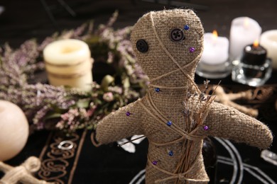 Photo of Voodoo doll with pins and dried flowers indoors, closeup