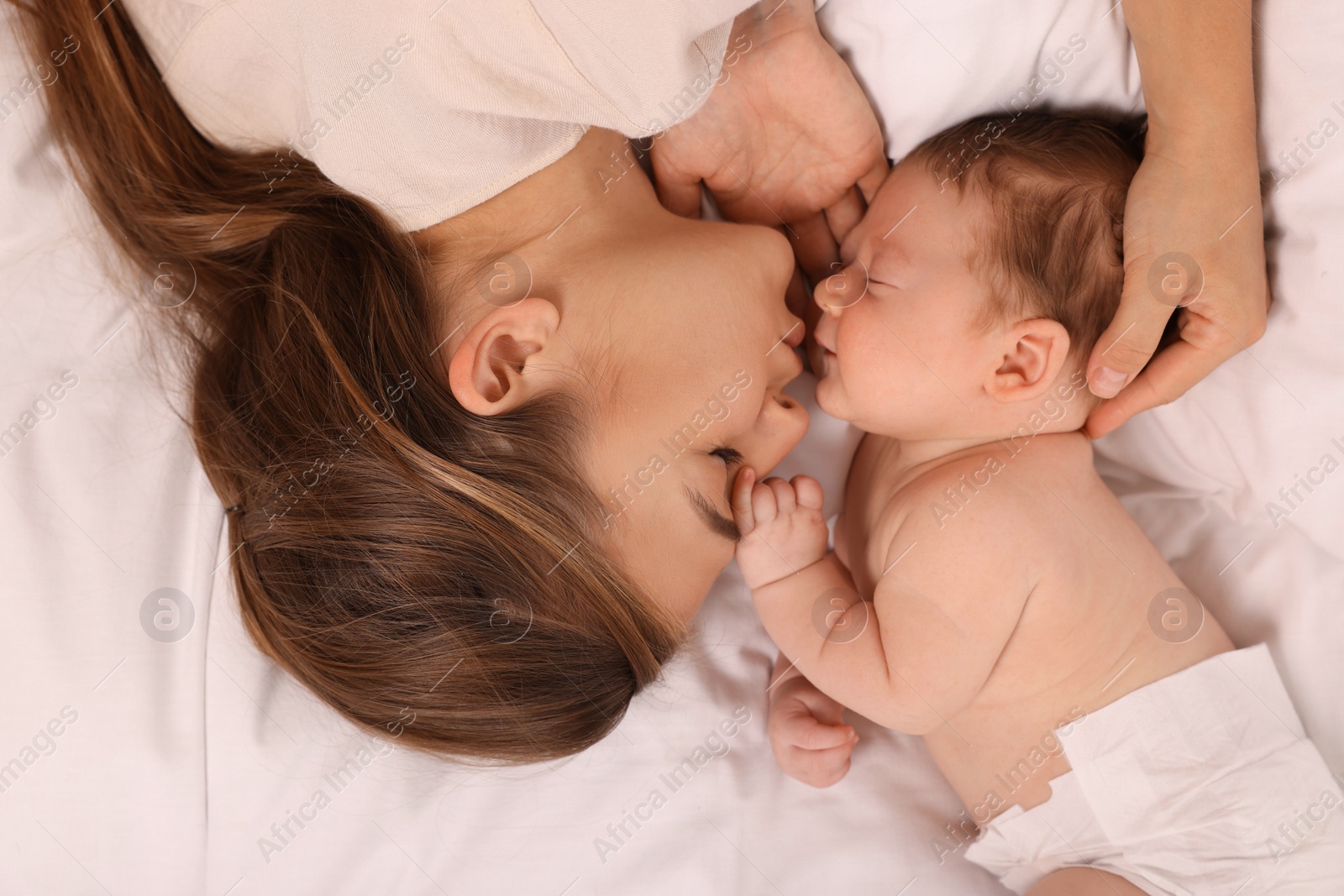 Photo of Mother and her cute newborn baby on bed, top view