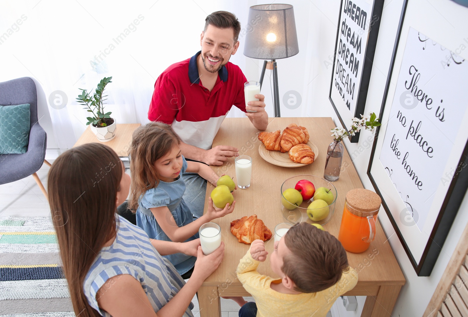 Photo of Happy family having breakfast with milk at table