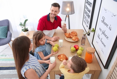 Photo of Happy family having breakfast with milk at table