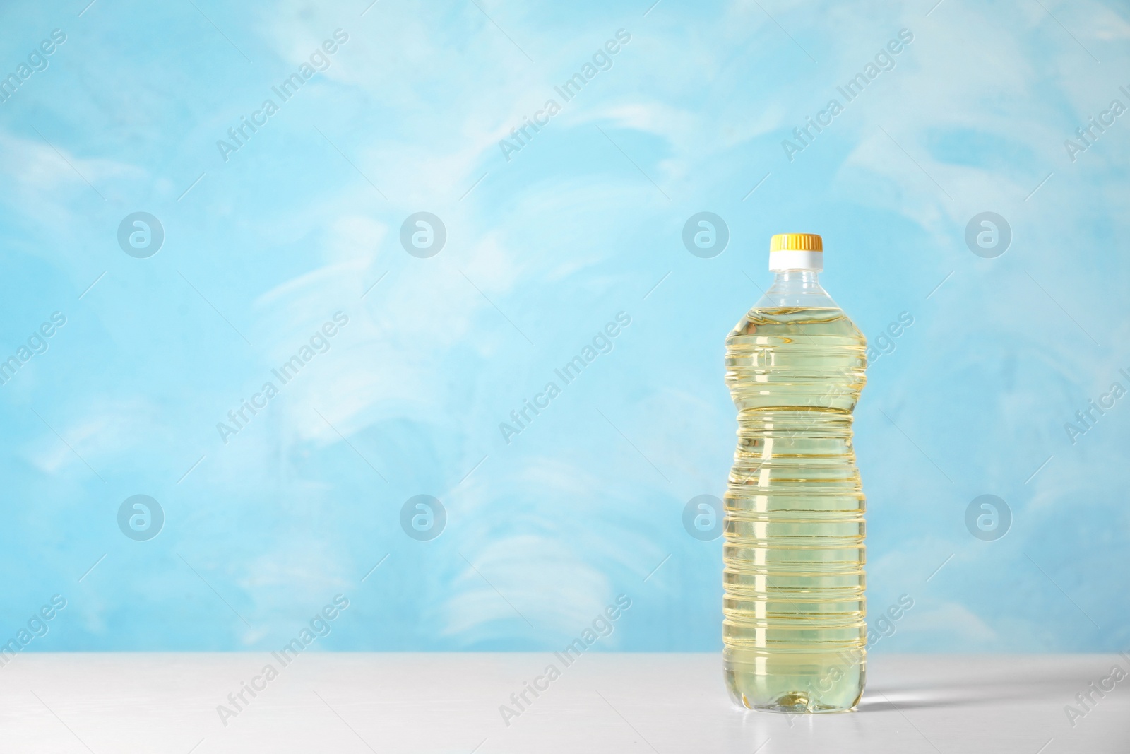 Photo of Bottle of oil on table against color background. Space for text