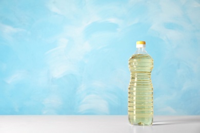 Bottle of oil on table against color background. Space for text