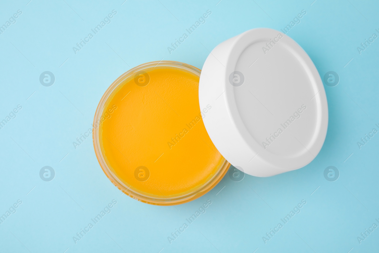 Photo of Open jar of petrolatum on light blue background, top view