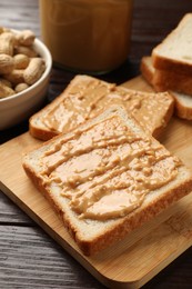 Photo of Delicious toasts with peanut butter on dark wooden table, closeup