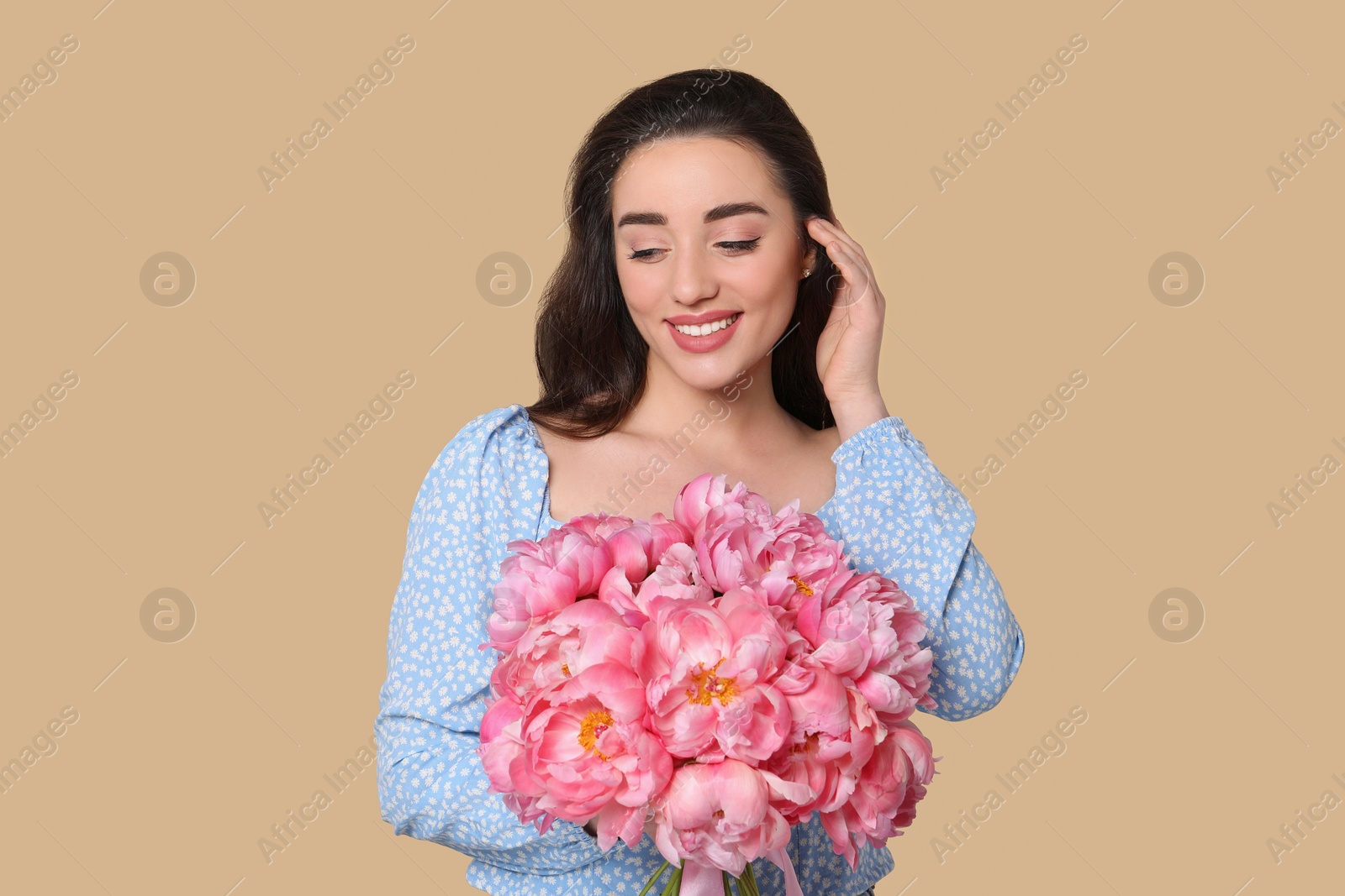 Photo of Beautiful young woman with bouquet of pink peonies on beige background