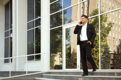 Photo of Handsome man talking on smartphone on city street