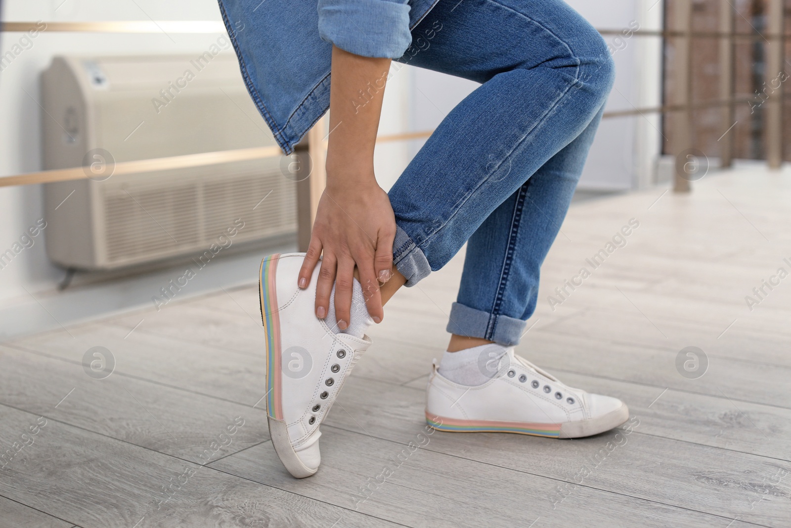 Photo of Young woman suffering from leg pain indoors, closeup