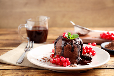 Photo of Delicious warm chocolate lava cake with mint and berries on wooden table