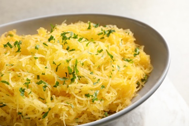 Photo of Bowl with cooked spaghetti squash on light background, closeup