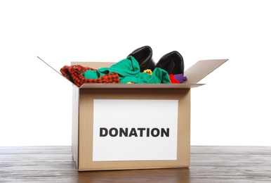 Donation box with clothes and shoes on table against white background