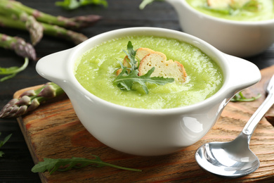 Photo of Delicious asparagus soup in bowl served on table