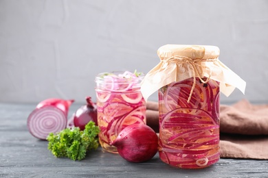 Photo of Jars of pickled onions on grey wooden table