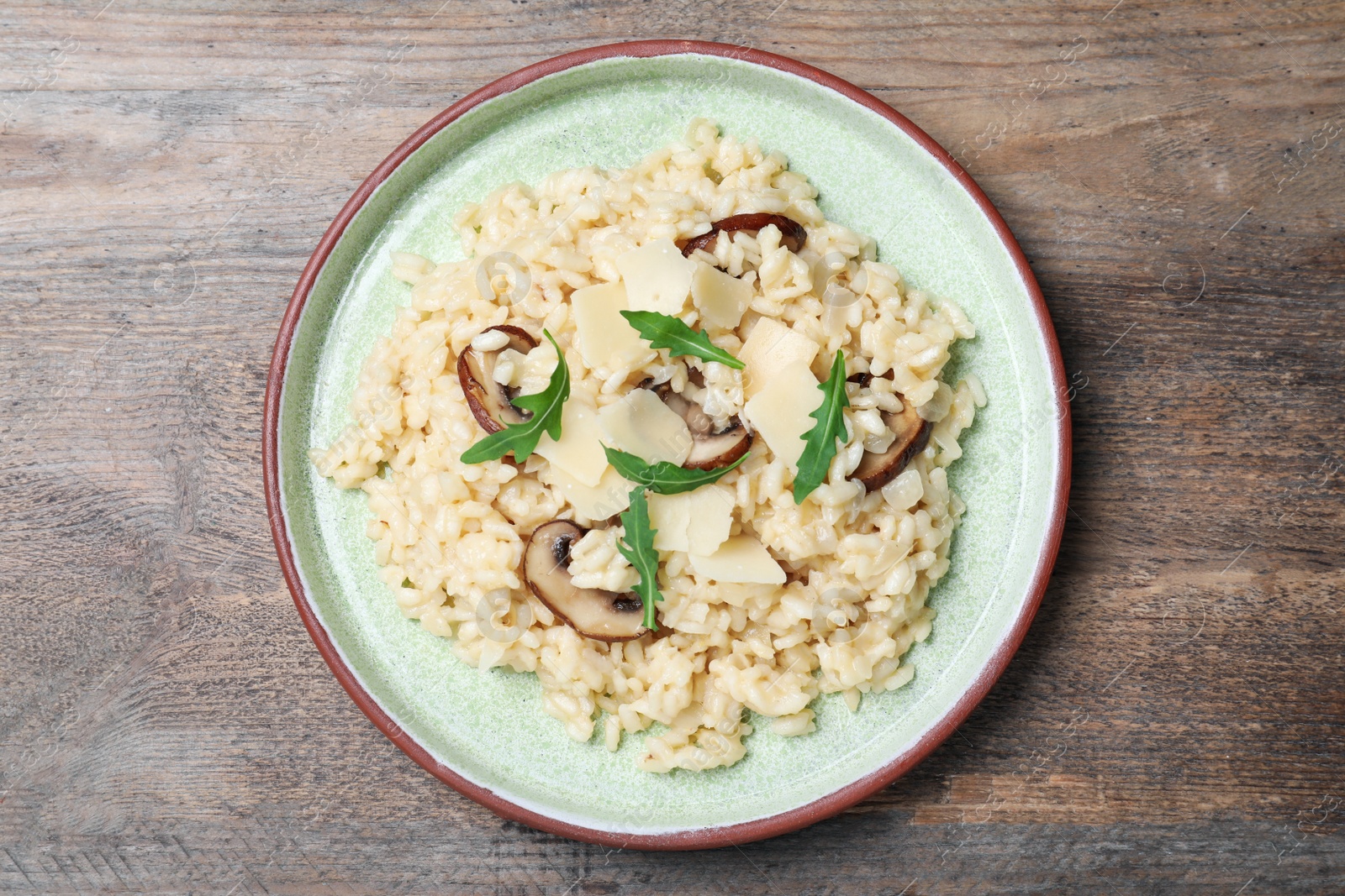 Photo of Delicious risotto with cheese and mushrooms on wooden table, top view