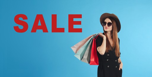 Image of Beautiful young woman with paper shopping bags and word SALE on light blue background. Banner design