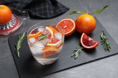 Photo of Delicious refreshing drink with sicilian orange and rosemary near fresh ingredients on grey table