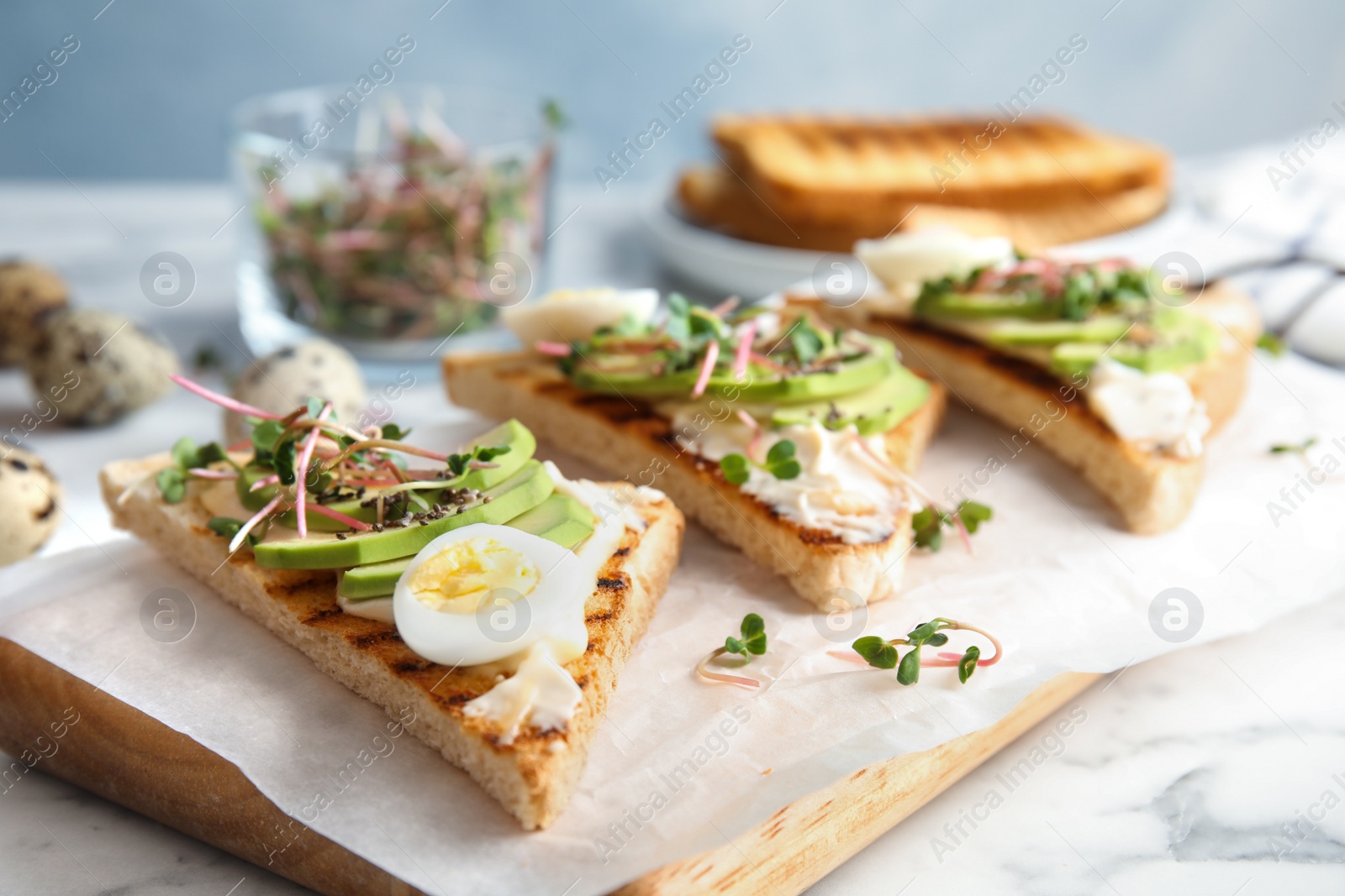 Photo of Tasty toasts with avocado, quail egg and chia seeds served on board