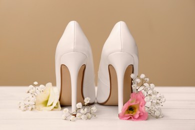 Women's shoes with beautiful flowers on beige wooden surface